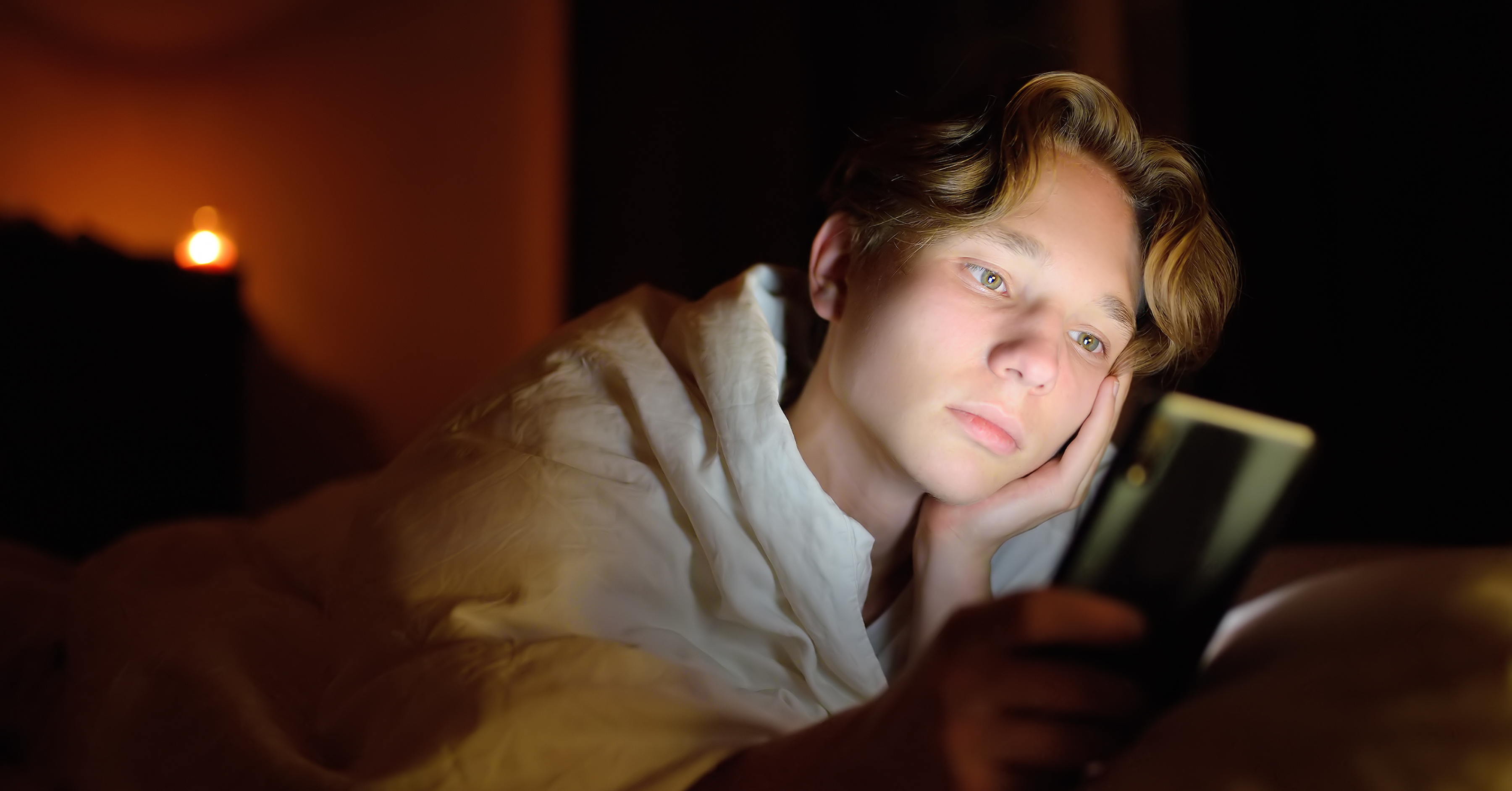 sad teen up late scrolling social media on phone