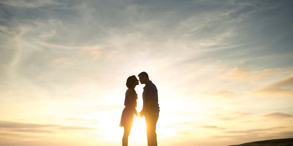 couple holding hands at a background of the sunset