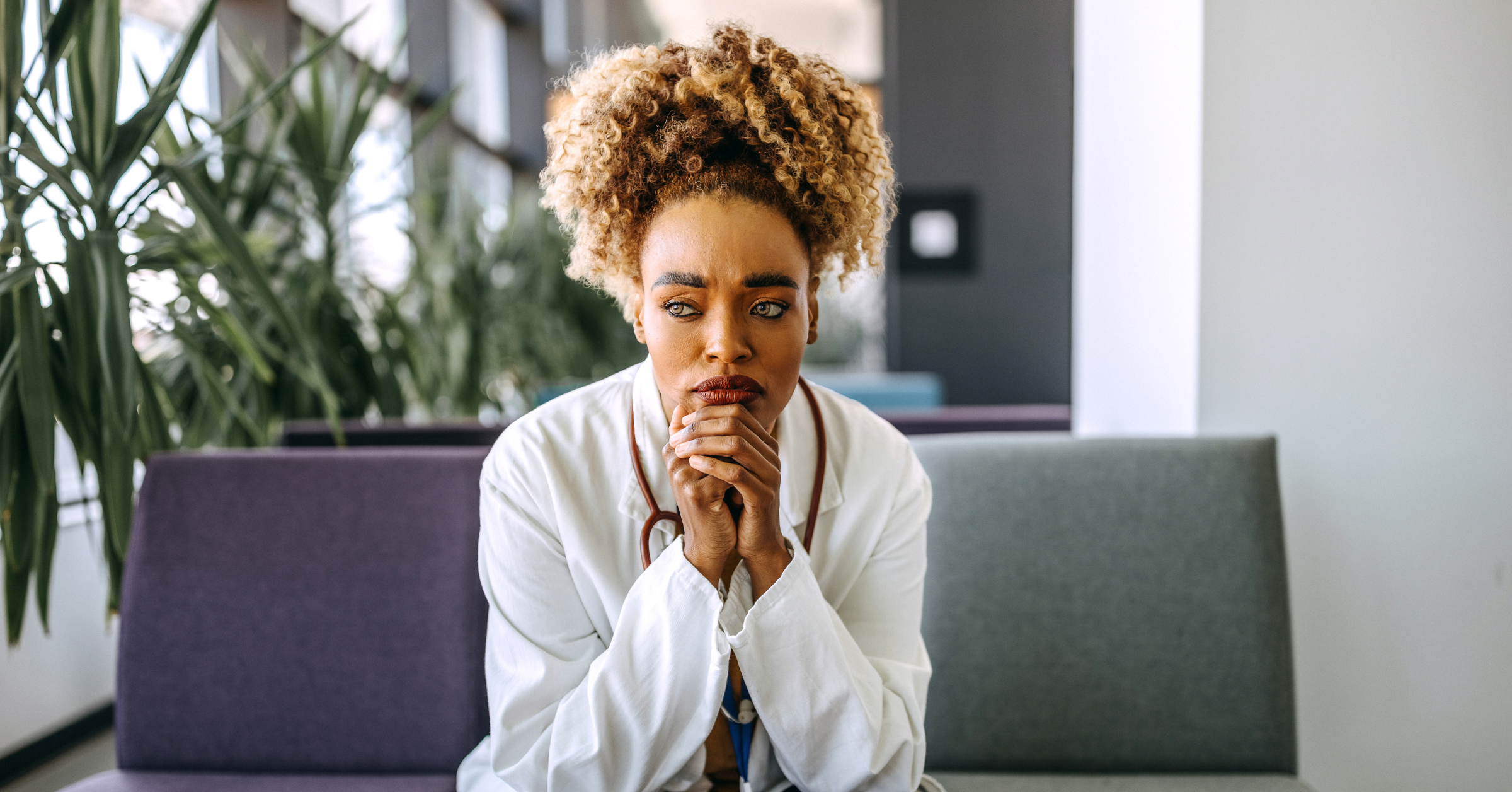 female healthcare worker in white coat and stethescope suffering from fatigue