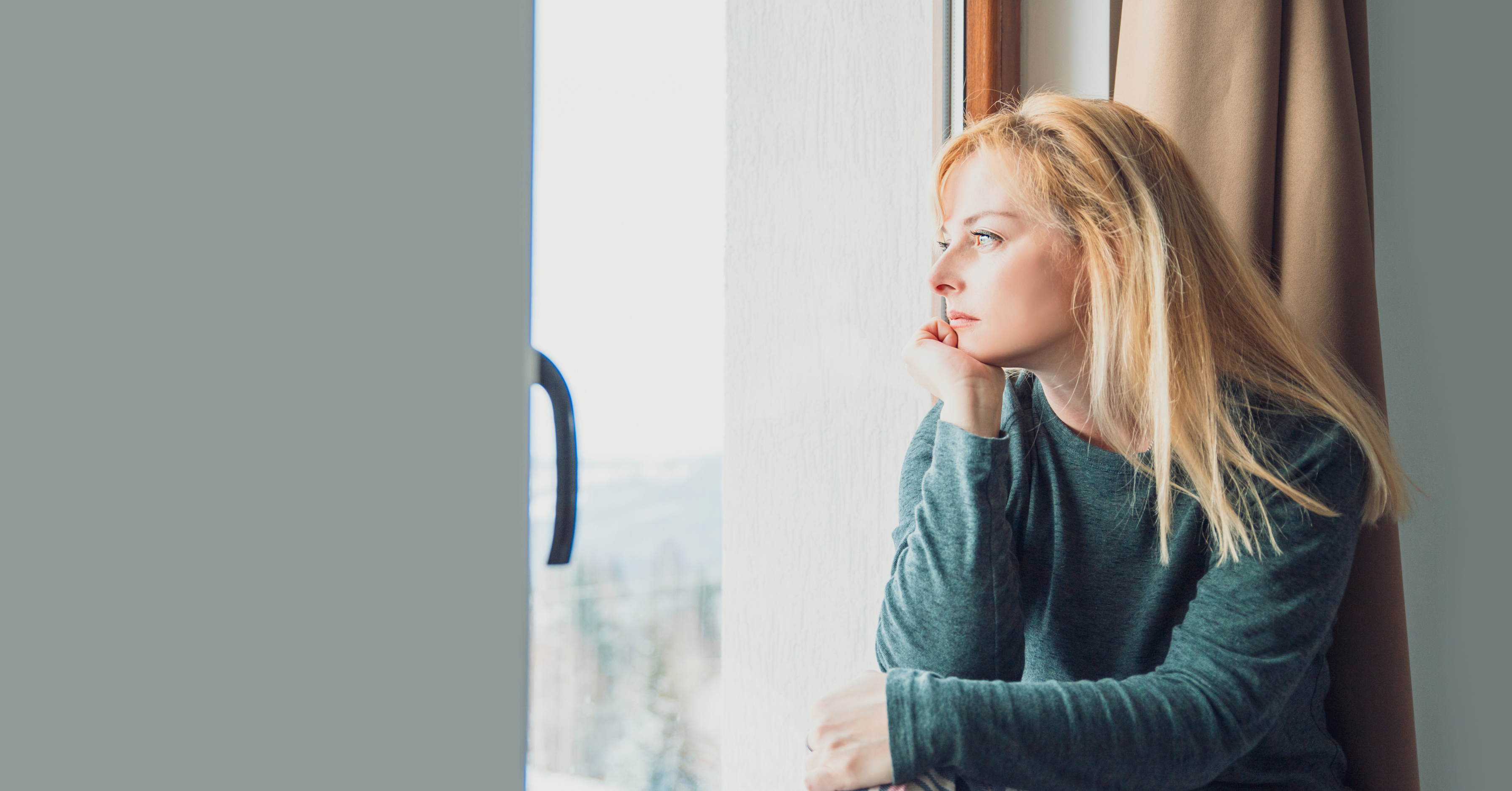 anxious depressed woman looking out window and thinking