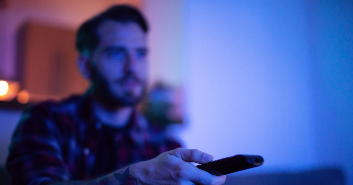 shadowy blue background of bearded male holding remote
