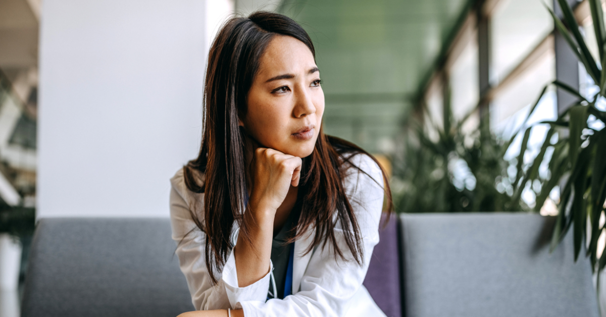 Stressed woman looking out window considering coping strategies.