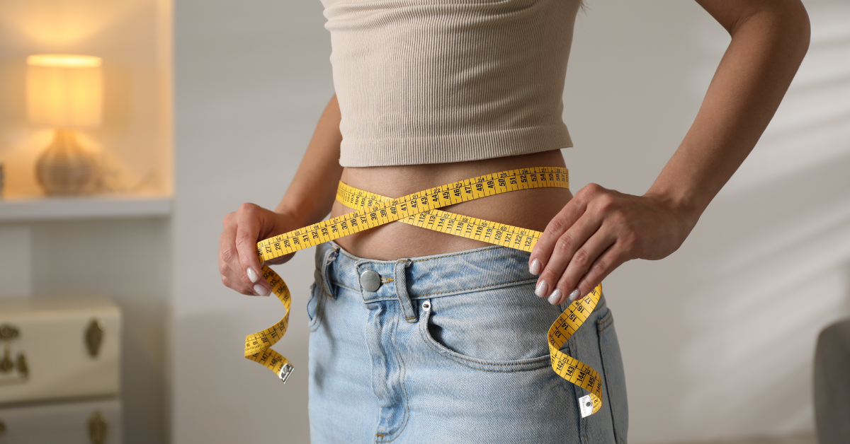 very thin female pulling measuring tape across waist