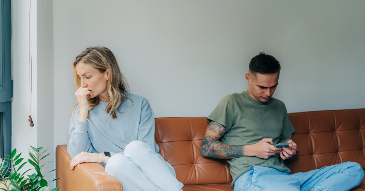 couple facing away from each other, woman feeling abandoned, man on phone